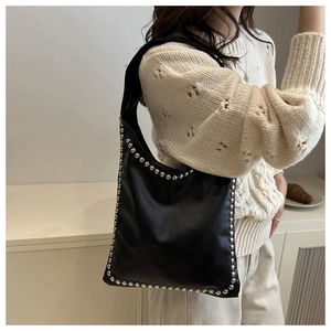 Close-up of black rivet-studded shoulder bag with silver hardware in a lifestyle setting
