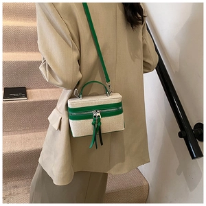 Detail of canvas box bag with green trim and long tassel zippers worn on body