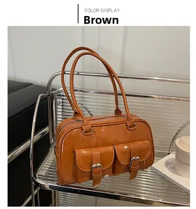 Detail of brown glossy leather shoulder bag with dual pockets and metal buckle decor
