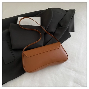 Detailed view of caramel brown faux leather baguette bag on a chic black blazer