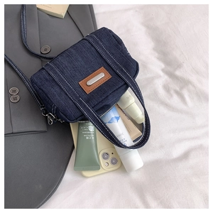 Detail of blue denim mini bag storage space with cosmetics and a leather patch