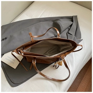 Internal view of a large brown leather tote bag with strawberry charm and zipper closure