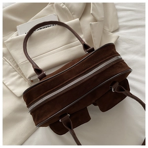 Vue de dessus du sac à main en daim marron foncé avec fermeture éclair argentée sur une veste