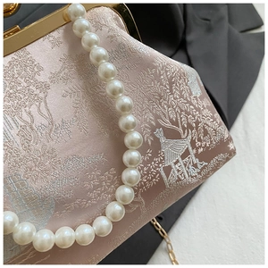 Detailansicht der rosa Stickerei und des Perlenstiels einer eleganten Abendtasche