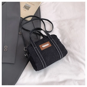 Macro shot of black denim mini tote with white contrast stitching and leather patch
