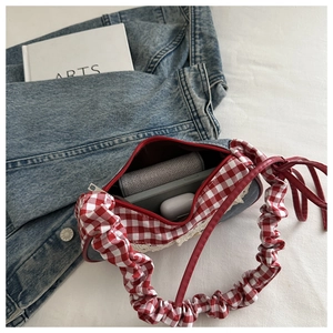 Détail du sac cabas avec poignée à carreaux rouges, texture denim et bordures en dentelle
