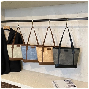 Detail of four matte canvas tote bags in neutral tones with fashion labels and leather straps