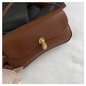 Close-up of golden metal twist lock on premium brown leather baguette shoulder bag