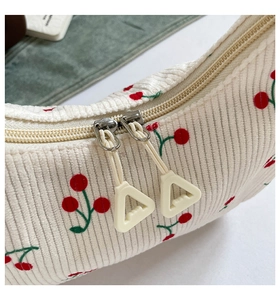 Detailaufnahme der Cord-Tasche mit Kirschmuster und silbernen Doppel-Reißverschlüssen