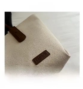 Detail of canvas tote bag showing weave texture and brown leather patch with FASHION logo