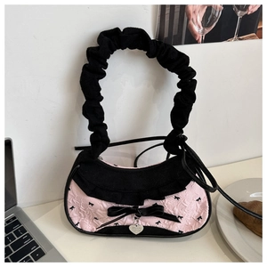 Détail du sac cabas en nylon rose avec nœuds noirs, volants et pendentif en forme de cœur