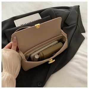 Detail view showing beige pebbled leather bag interior with gold clasp and essentials