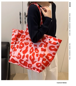 Detail of red leopard print canvas tote bag featuring buttoned front pocket and rivets