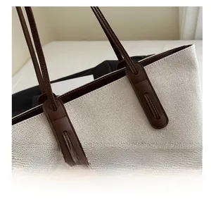 Detail of high-density canvas tote bag with brown leather handles and FASHION logo