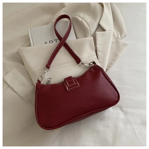 Detailed macro view of burgundy underarm bag with lychee texture and contrast stitching