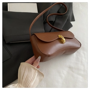 Detailed close-up of brown leather shoulder bag with golden metallic twist-lock closure