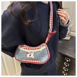 Détail du sac bandoulière en denim avec bordure à carreaux rouges, dentelle et broderie