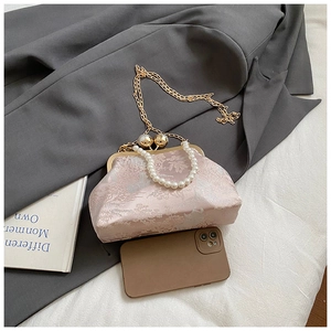 Detailaufnahme der rosa Brokat-Sticktasche mit Perlengriff und goldener Kette