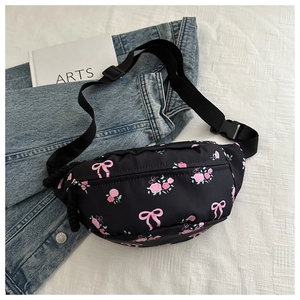 Detalle de la linda riñonera negra con flores y correa ajustable sobre chaqueta vaquera