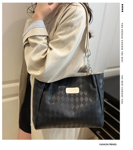 Detail of black quilted leather tote bag featuring chain strap and metallic brand logo