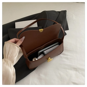 Detail shot showing the spacious interior of the brown leather shoulder bag with gold hardware