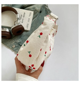 Detail der cremefarbenen Cord-Schultertasche mit roten Kirschstickereien und Reißverschluss