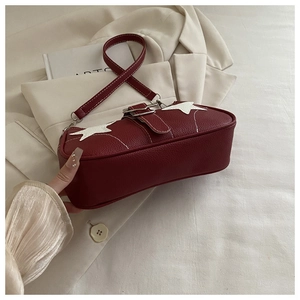 Detail of burgundy lychee leather shoulder bag with white star and metal buckle accents