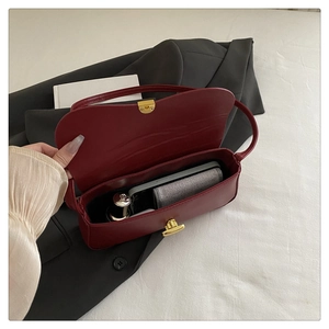 Detail view of burgundy shoulder bag interior showing phone, lipstick and gold twist lock