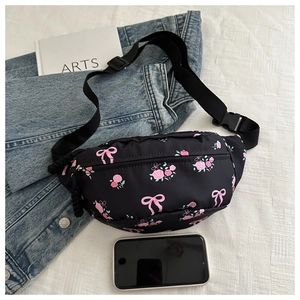 Florale crossbodytas met roze strikken en rozen naast een smartphone voor de maatreferentie