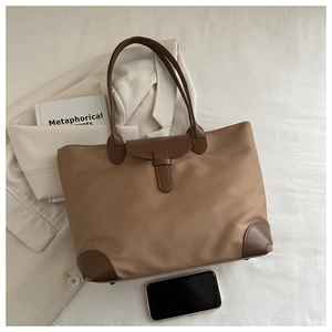 Vista dall'alto di una grande borsa tote in nylon con manici in pelle e un blazer