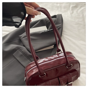 Detail of burgundy glossy leather underarm bag with double front buckle pockets