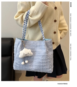 Détail du cabas en tweed bleu clair avec poignée tissée violette et charm nuage blanc