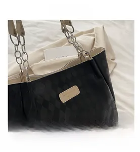 Close-up of black checkerboard tote bag with silver chain strap and leather logo patch
