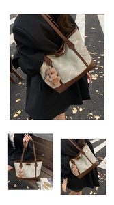 Close-up of canvas tote bag featuring brown faux leather trim and a plush bear pendant