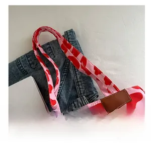 Detail of pink cow print canvas tote bag with brown leather label and reinforced handles