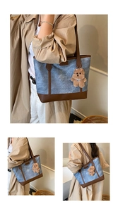 Detail of vintage denim tote bag with brown leather trim and cute bear charm pendant