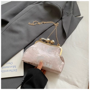 Detail of pink jacquard evening bag featuring pearl clasp and gold chain strap