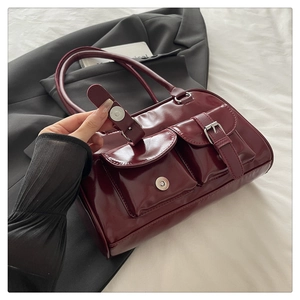 Detail showing magnetic snap closure on deep red glossy leather shoulder bag
