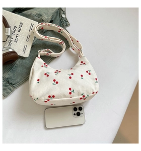 Detail der weißen Cord-Schultertasche mit Kirsch-Print und verstellbarem Trageriemen