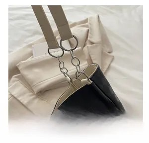Close-up of black quilted tote bag featuring silver chain hardware and beige leather strap