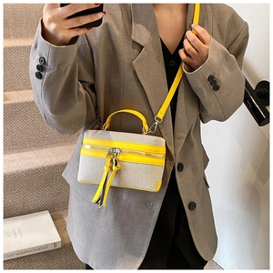 Detail of canvas box bag with yellow leather trim and tassels in a crossbody style