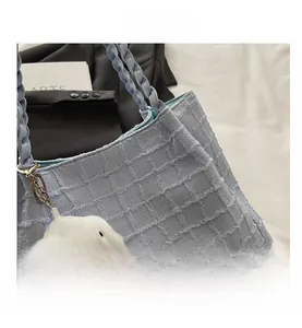 Détail du sac fourre-tout bleu clair avec texture bulle, poignée tressée et charme nuage