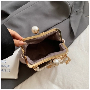 Detailaufnahme des Perlen-Verschlusses und der Goldkette an einer bestickten Muscheltasche