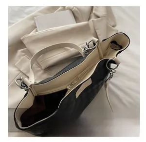 Close-up of diamond pattern tote bag interior with branded leather tag and silver chain