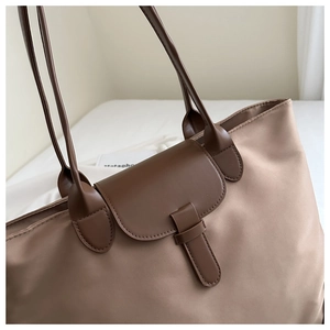Dettaglio della borsa tote in nylon marrone con chiusura in pelle e trama liscia