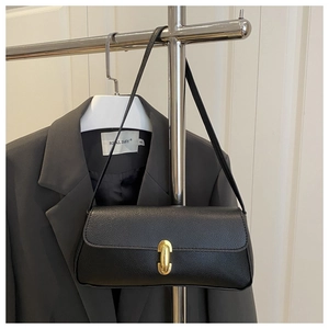Close-up of black lychee grain leather underarm bag with gold oval metal clasp
