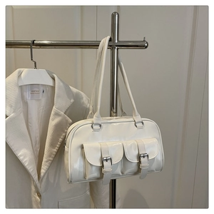 Close-up of cream patent leather bowling bag with twin flap pockets and silver buckles