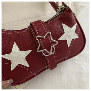 Nahaufnahme der roten Leder-Achseltasche mit weißen Stern-Applikationen und Metallschnalle
