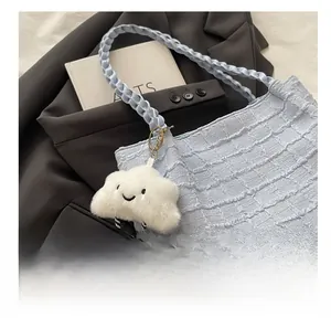 Vue détaillée d'un porte-clés nuage blanc avec smiley sur un cabas bleu à carreaux