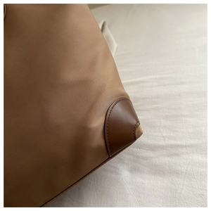 Dettaglio borsa tote in nylon marrone con angolo in pelle e cuciture di precisione
